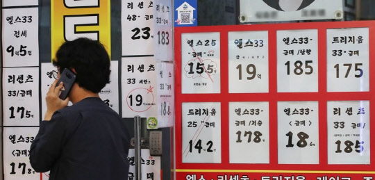 한 시민이 아파트 급매물 시세가 걸린 부동산공인중개업소 게시판 앞에서 전화통화를 하고 있다.<연합뉴스>